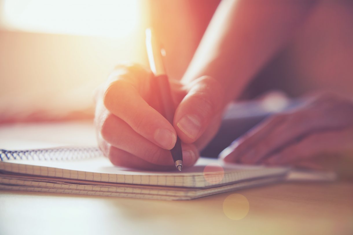 female hands with pen writing on notebook